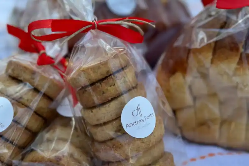Múltiples bolsas transparentes rellenas con galletas de mantequilla en su interior, cerradas con un lazo rojo.